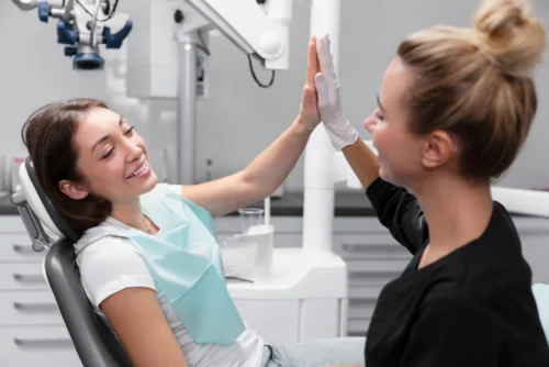 Endodont izvaja postopek endodontskega zdravljenja pod mikroskopom. Na zaslonu je prikazana rentgenska slika zoba z očiščenimi koreninskimi kanali